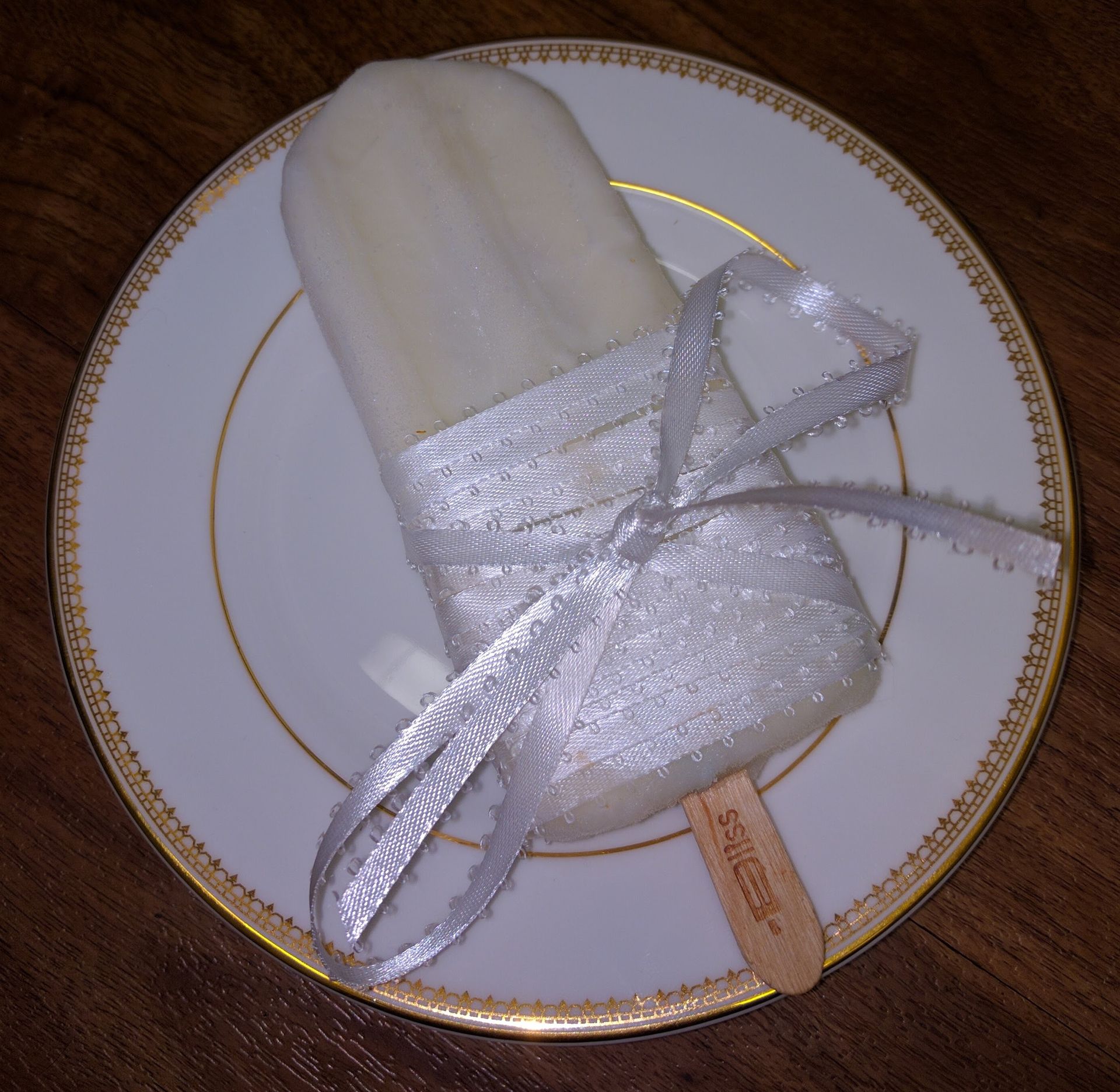 A white and gold plate with a popsicle on it