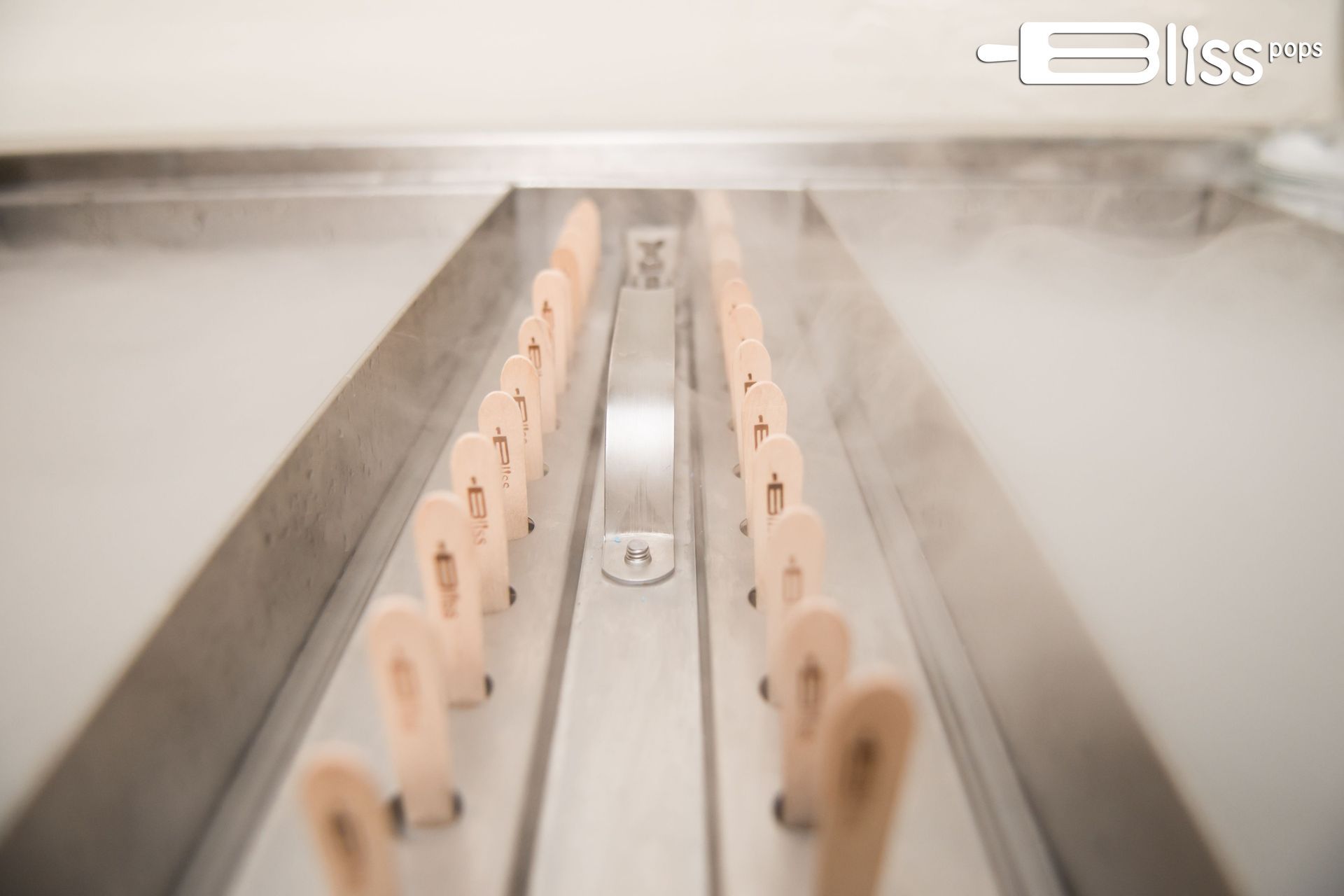 A bunch of popsicle sticks are lined up on a conveyor belt.