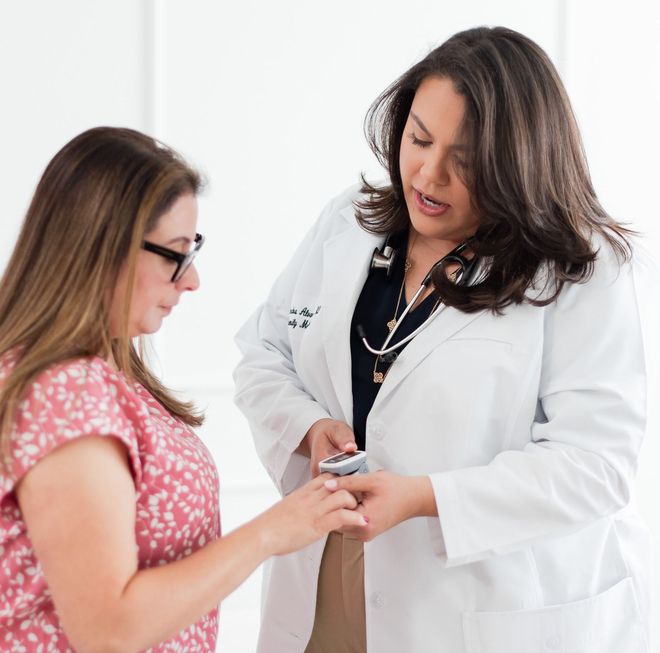 A doctor is talking to a patient who is getting her oxygen checked.