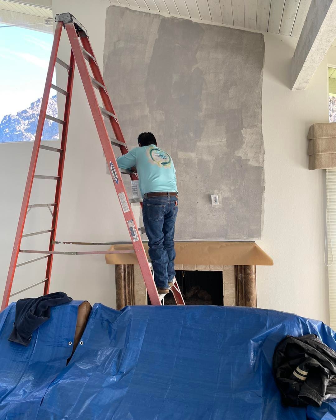Image of someone of the team of desert innovations painting and handyman in Coachella Valley that is in the process of installing a rock wall over a fireplace. 