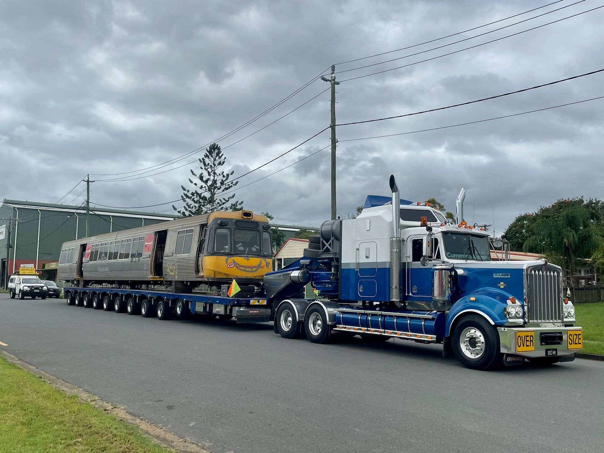 A large blue and white semi-truck hauls a train car down a street — ECC Heavy Haulage in Ormeau, QLD
