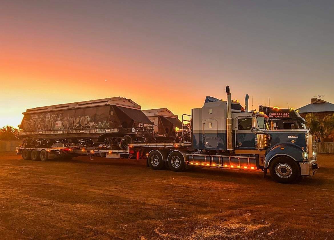 Semi-truck and trailer parked at sunset. Blue cab, loaded trailer on dirt — ECC Heavy Haulage in Ormeau, QLD