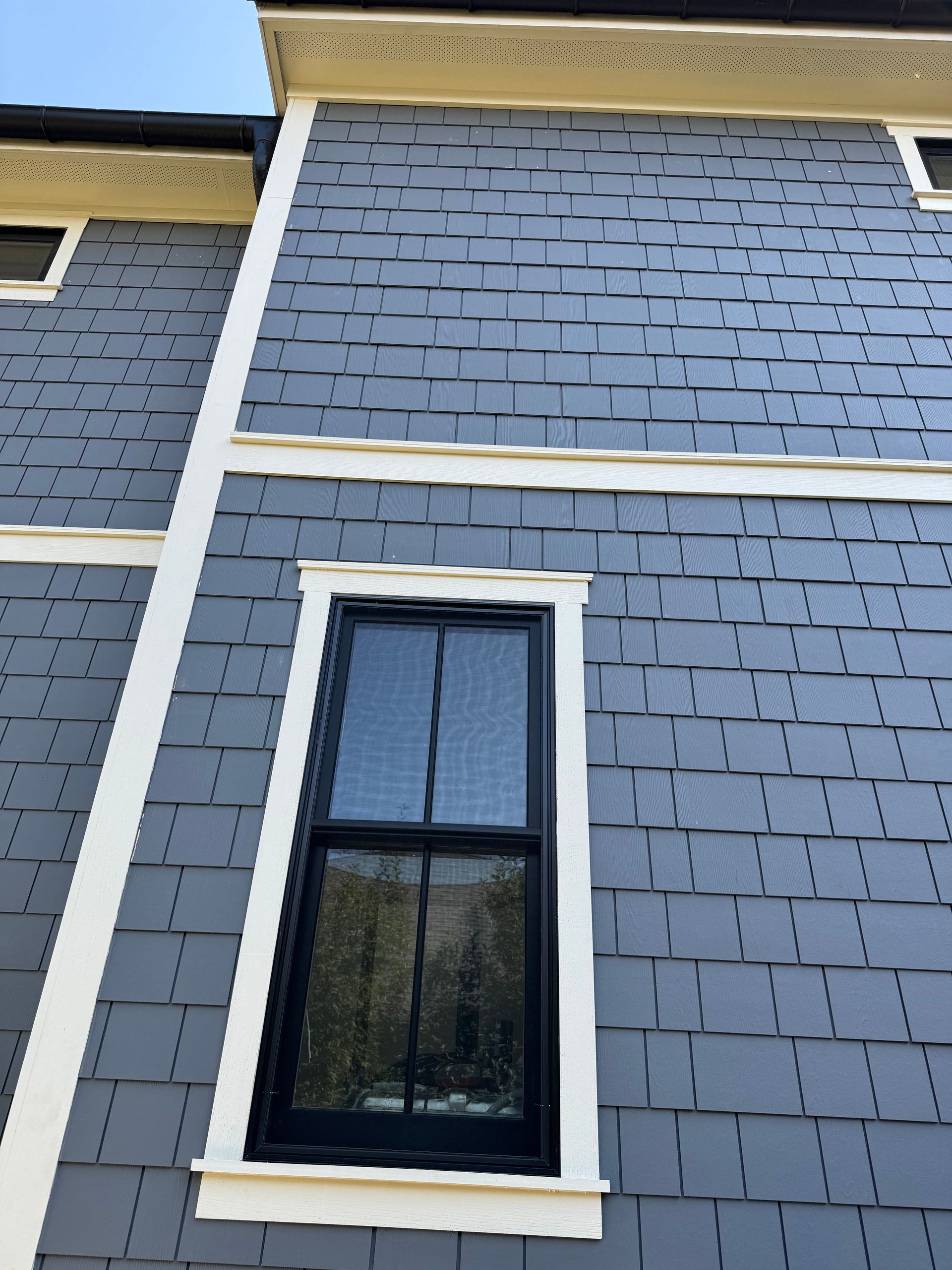 Gray house exterior with white trim and a small black-framed window.