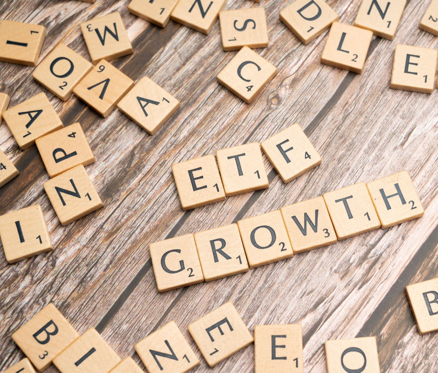 Scrabble tiles spelling “ETF GROWTH” on a rustic wooden surface