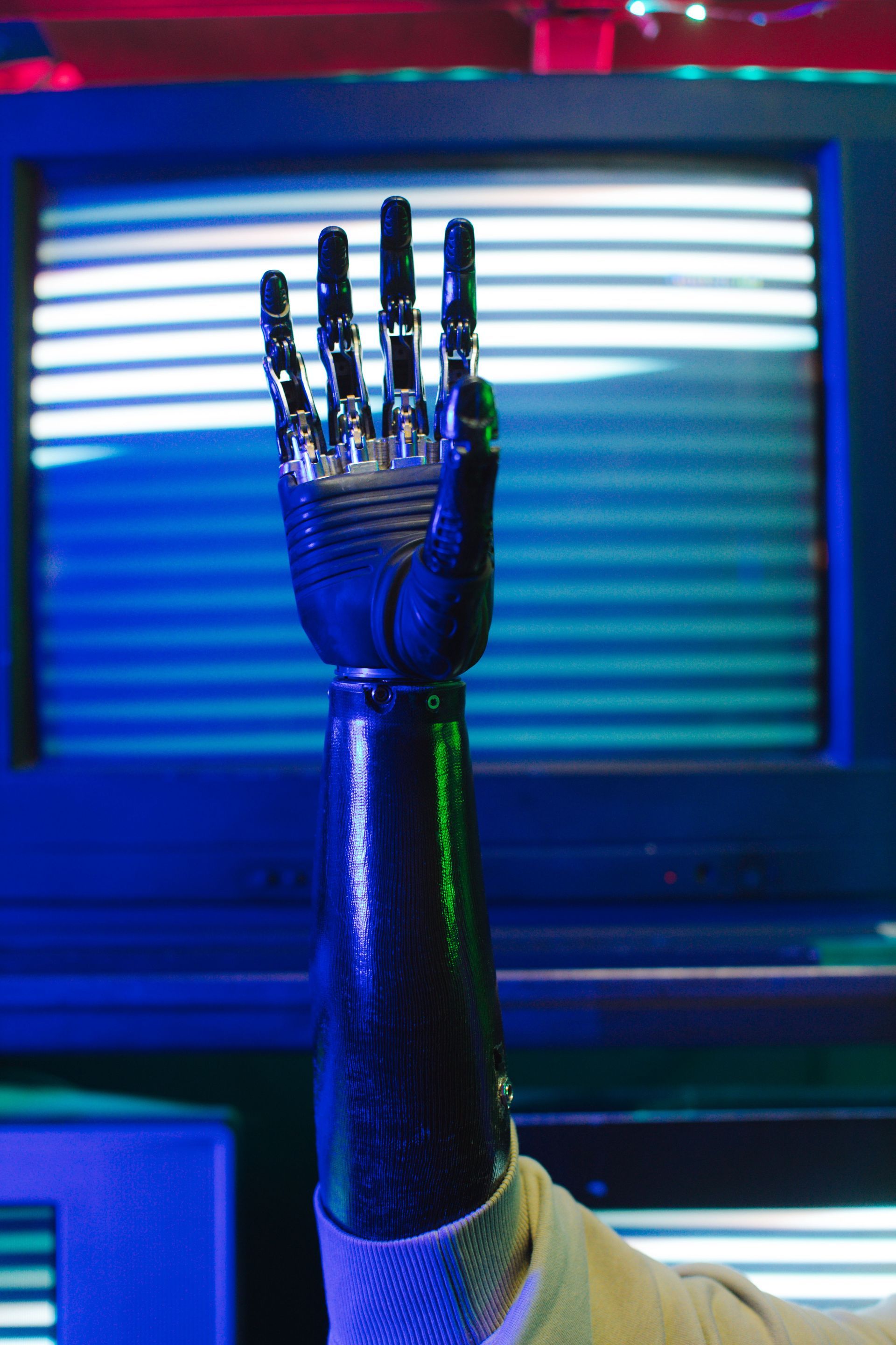 Metallic robotic hand raised against blue neon lights and striped screen background
