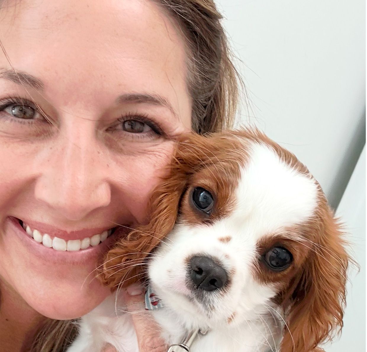 Girl holding a brown puppy named Rosie wearing a pink bow. Other children are in the background outside.