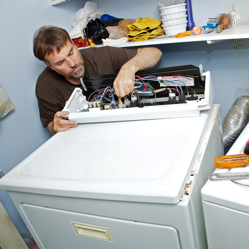 Technician repairing the control panel of a white appliance in a laundry room