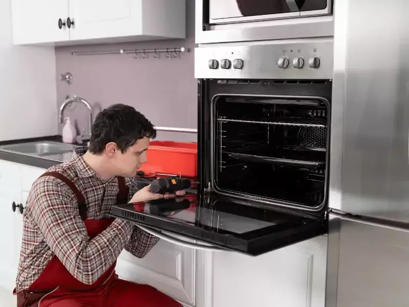 Person inspecting a stainless steel oven with the door open in a modern kitchen