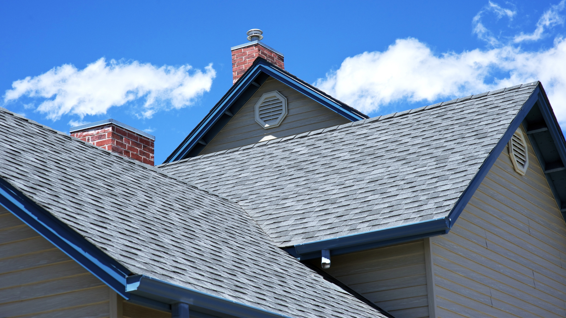 A house with a gray roof and a chimney on top of it.