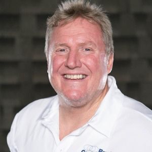 A man in a white shirt is smiling for the camera.