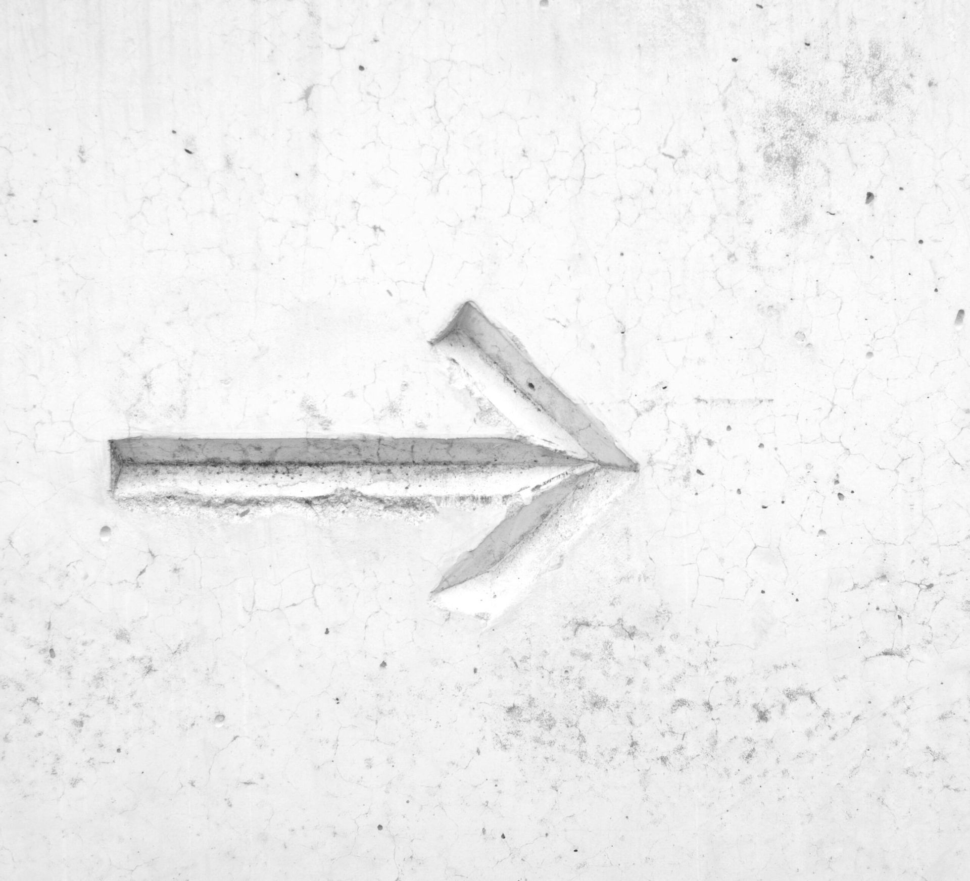 Arrow carved into a white, textured wall, pointing right.