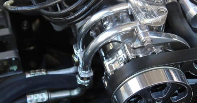 A close up of a power steering pump on a car engine.