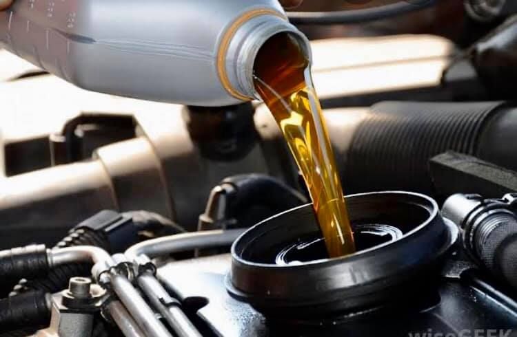 A person is pouring oil into a car engine.
