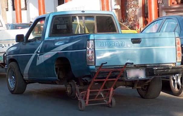 A blue nissan truck with a shopping cart attached to it
