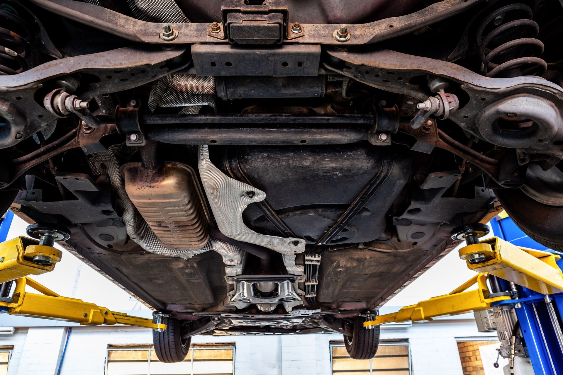 The underside of a car on a lift in a garage.