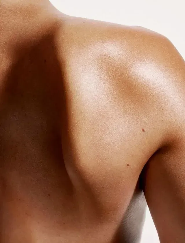 Close-up of a bare shoulder and upper back against a light background.