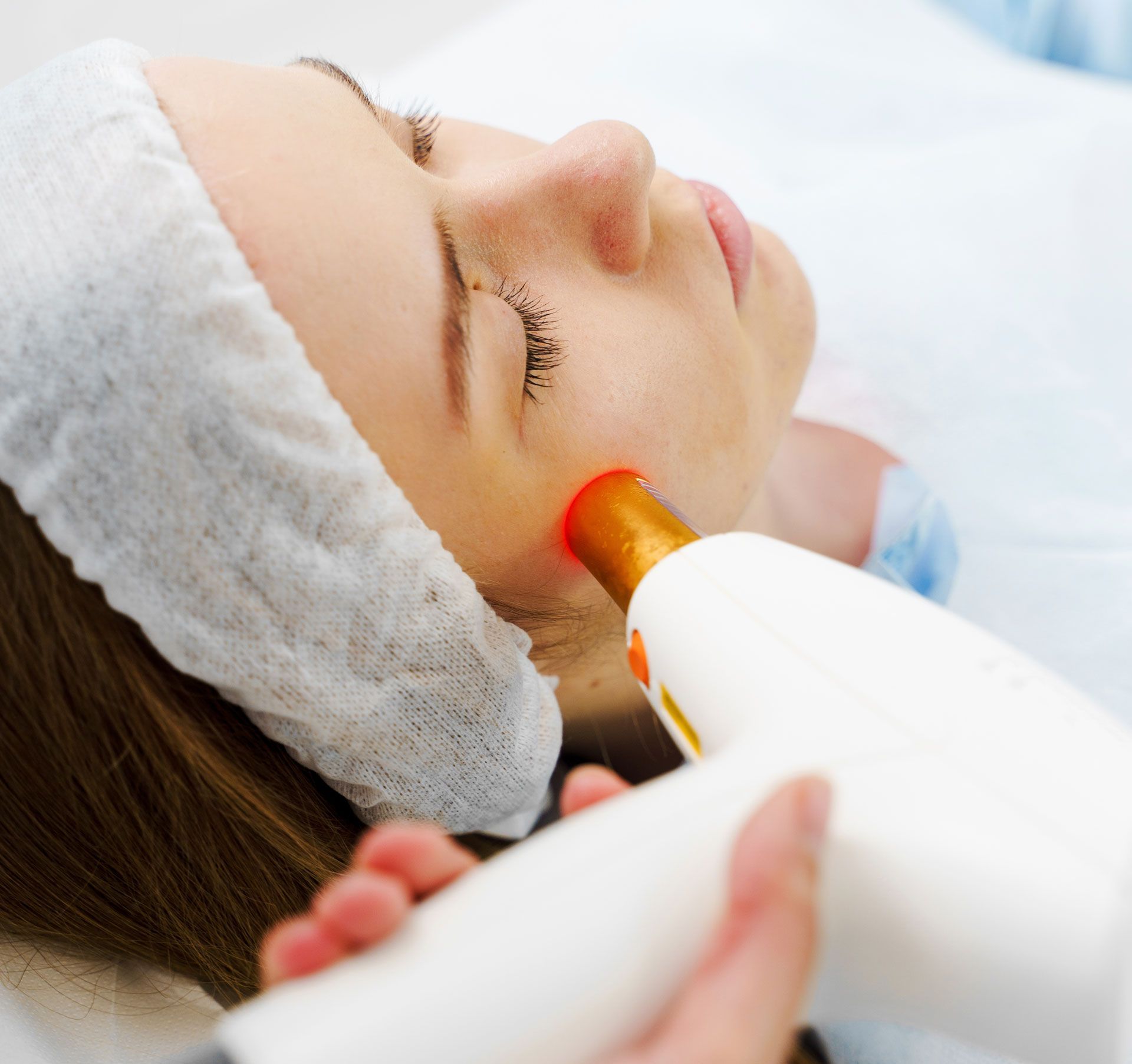 Woman receiving facial treatment with a handheld beauty device on her cheek