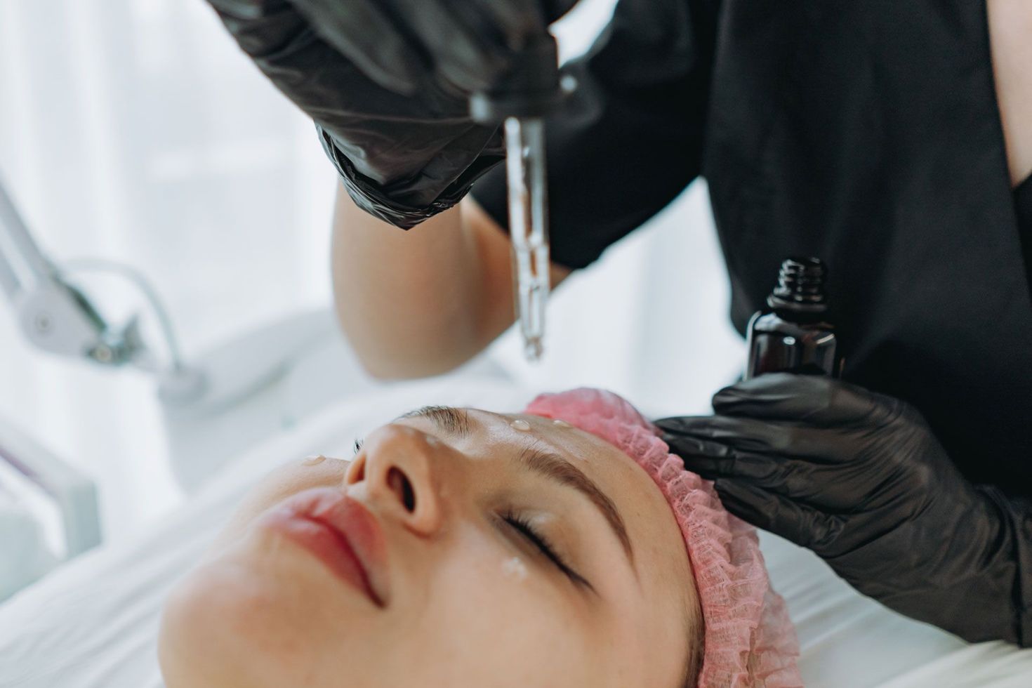 Cosmetic procedure on a woman’s forehead with a handheld device and gloved hands