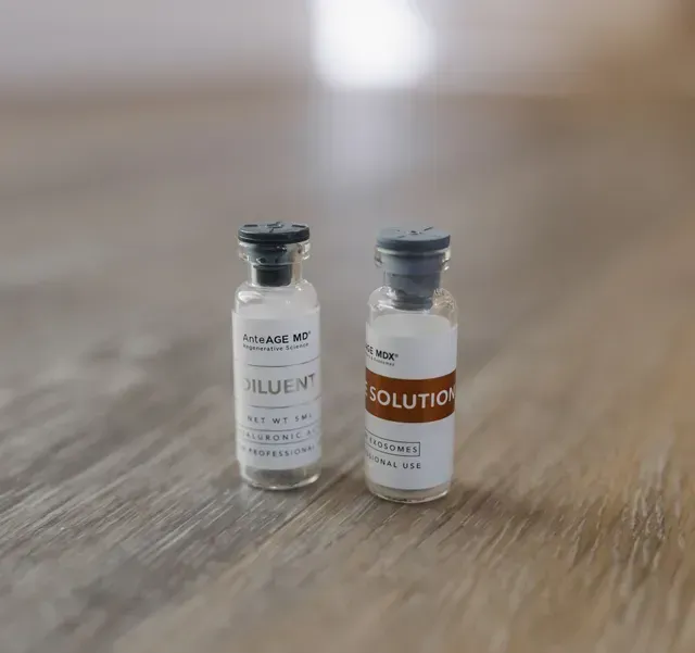 Two small glass vials on a wooden surface, labeled “DILUENT” and “SOLUTION.”