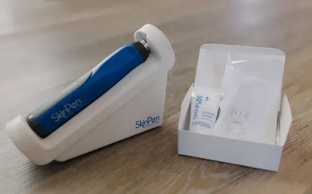 Blue grooming tool in a white case beside an open box on a wooden surface