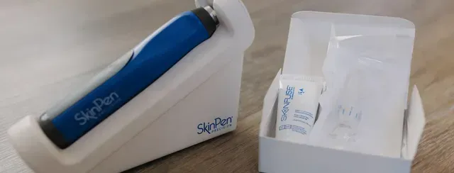Blue electronic device in a white charging case next to an open box of accessories