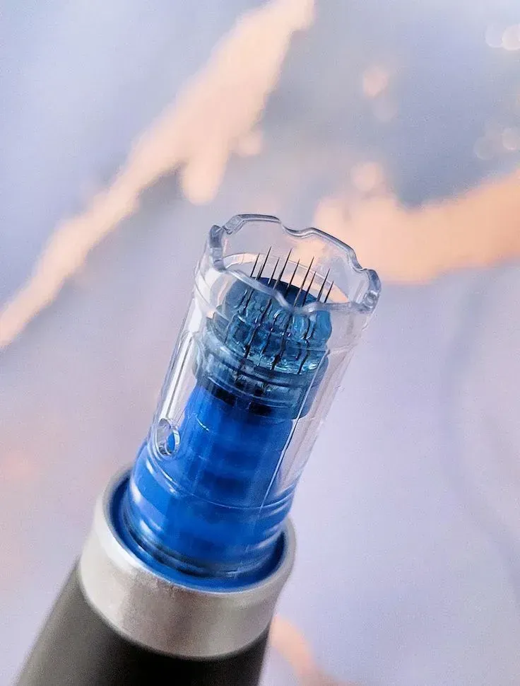 Close-up of a blue skincare device tip with a clear cap against a soft pastel background