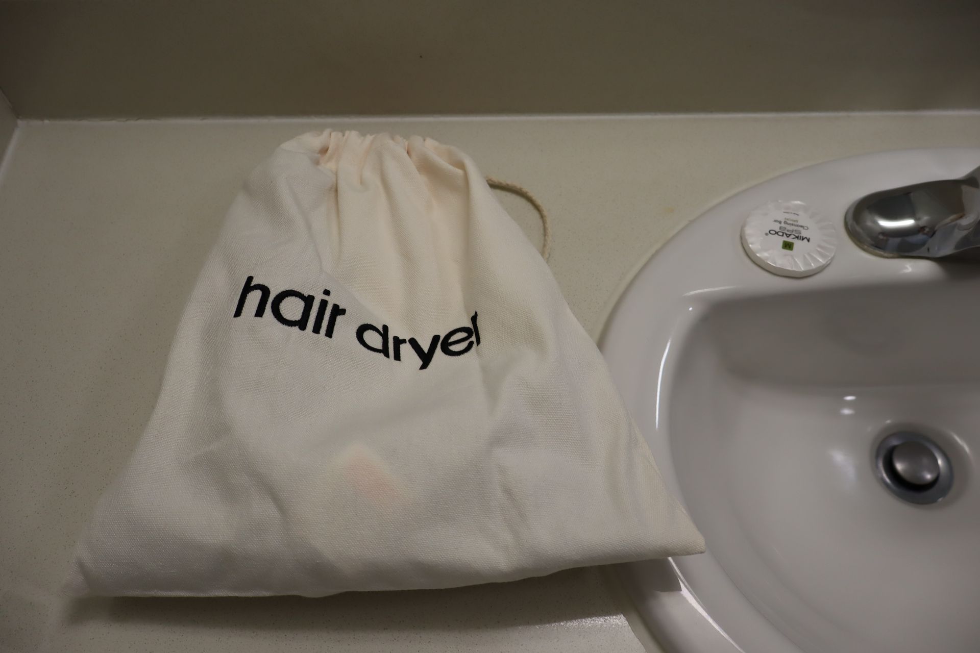 White hair dryer bag beside a sink on a bathroom counter