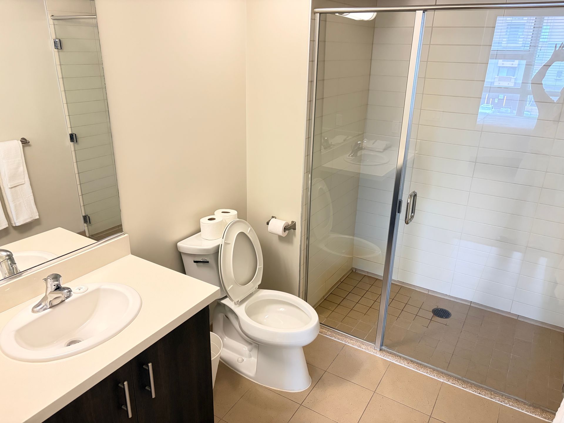 Bathroom with sink, toilet, and glass shower stall on the right.