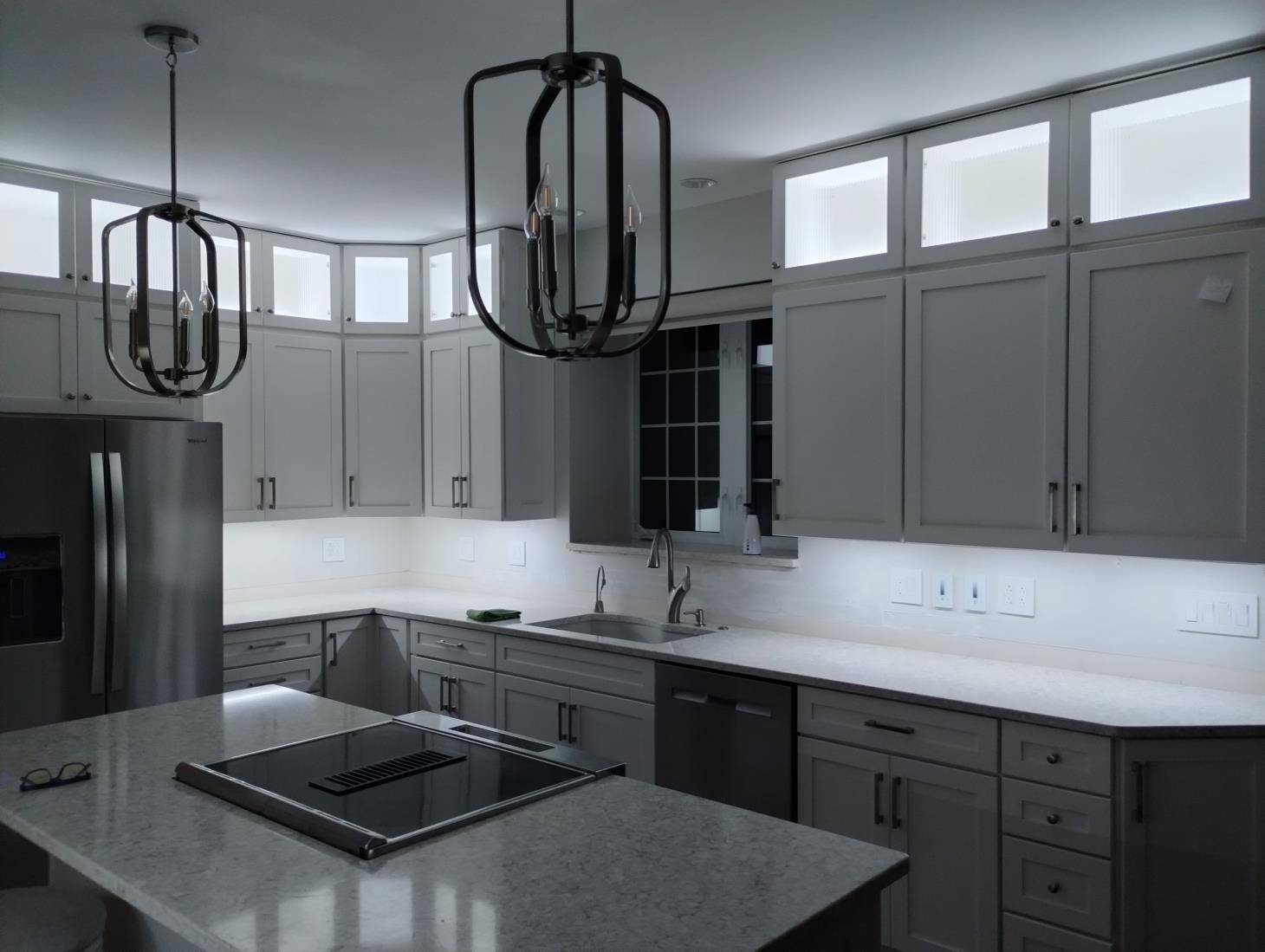 Modern gray kitchen with island, stainless steel appliances, pendant lights, and large windows