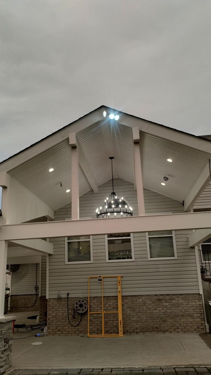 White building entrance with gabled roof, lit windows, and bicycle stands in front