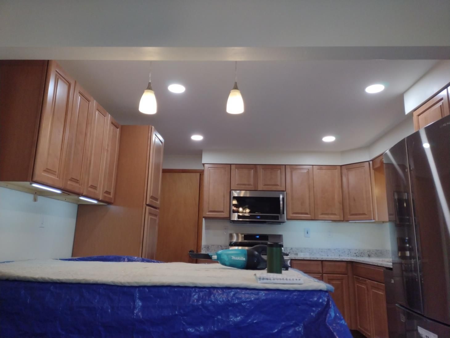 Modern kitchen with wood cabinets, stainless appliances, recessed lights, and a blue-covered island countertop
