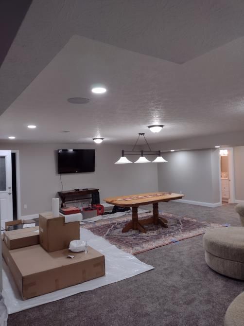 Spacious basement living room with sofa, coffee table, wall TV, and recessed lighting