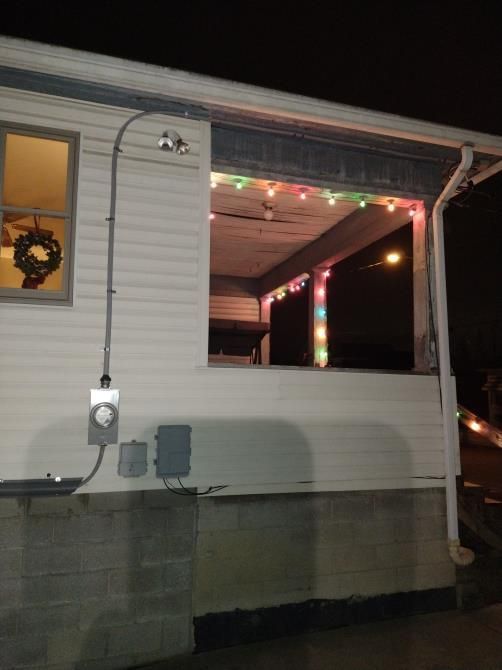 House porch with colorful Christmas lights and a wreath on the window at night