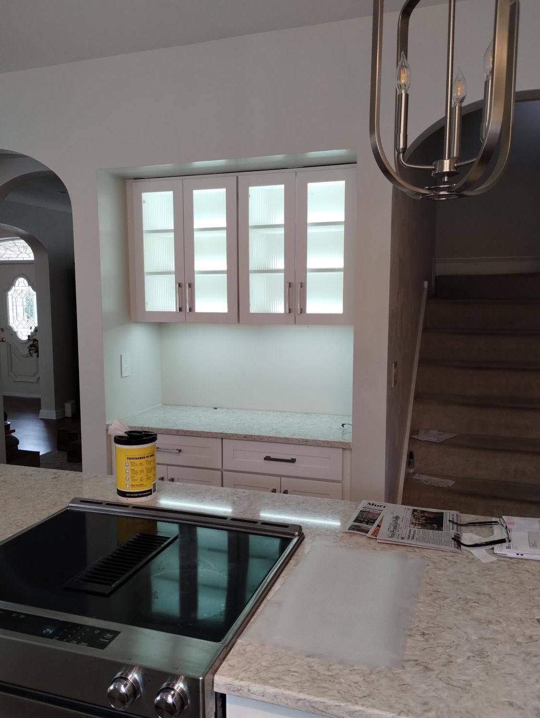 Modern kitchen with black cooktop, white cabinets, granite countertop, and a pass-through window.