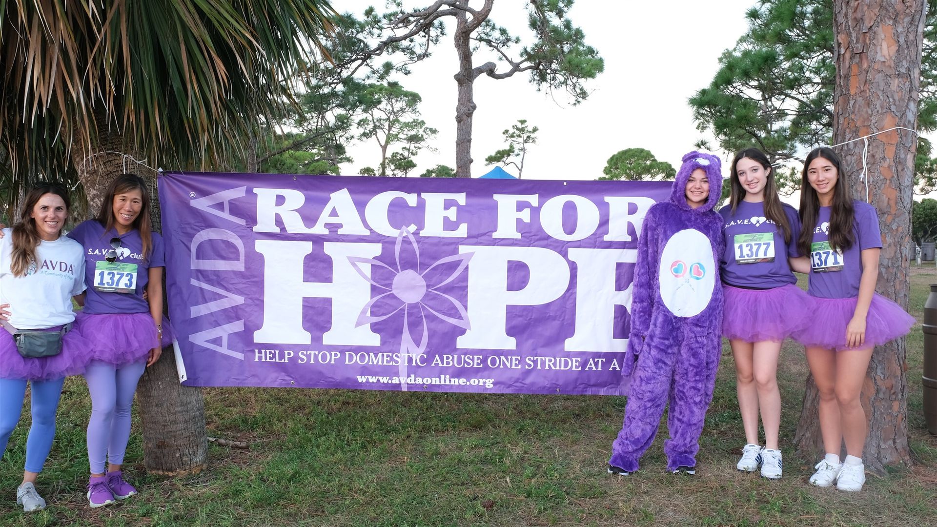 A group of girls are standing in front of a sign that says race for hope.