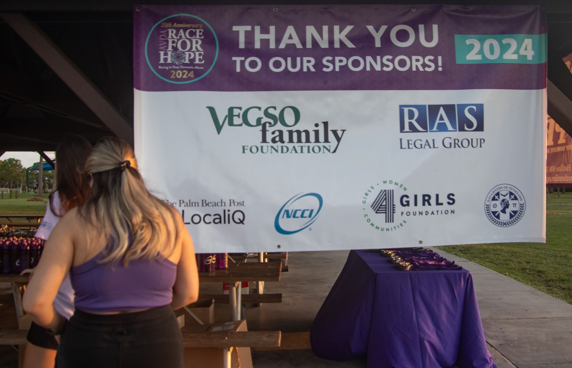 A woman stands in front of a sign that says thank you to our sponsors