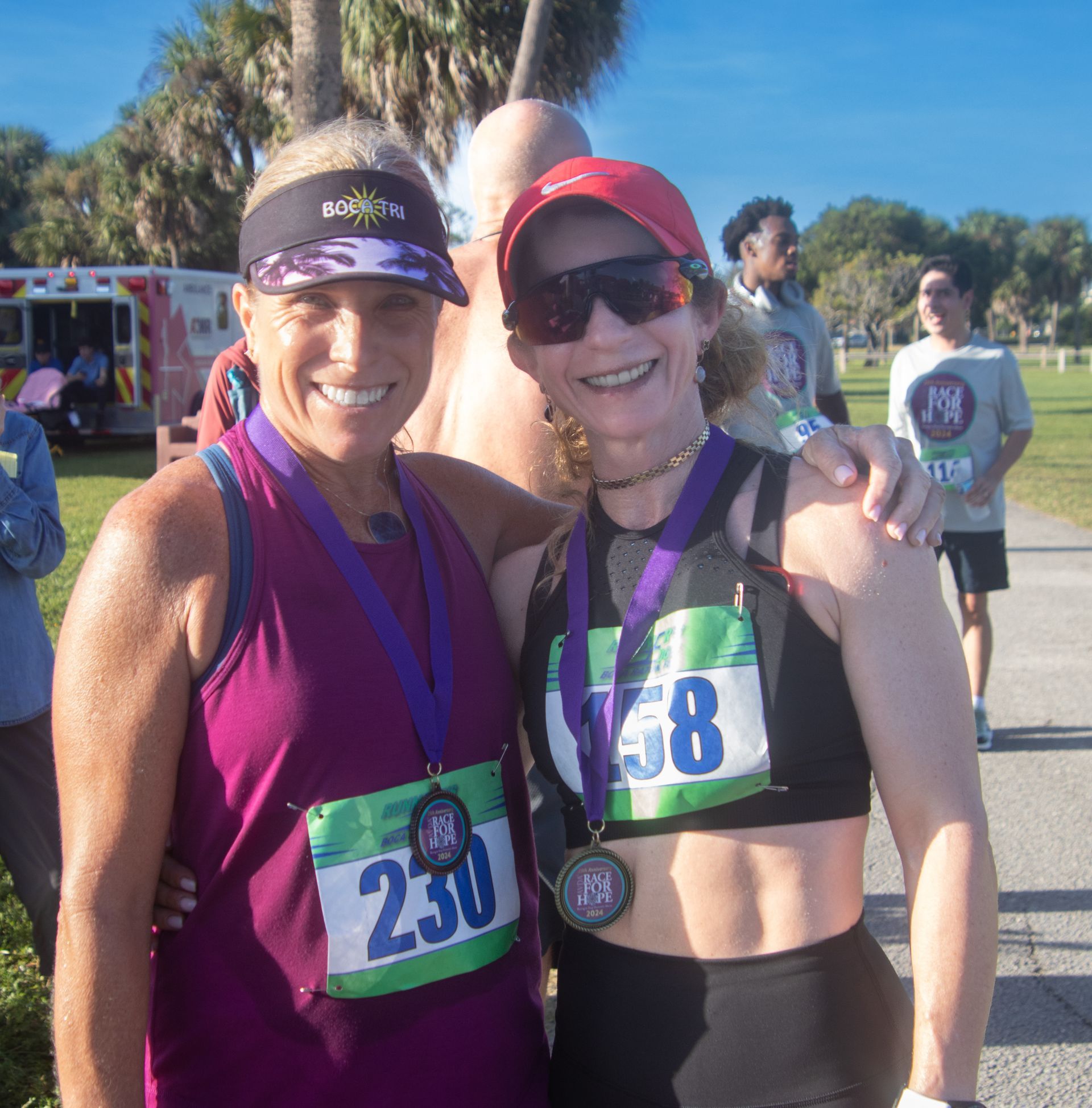 Two women posing for a picture with one wearing a tag that says 230