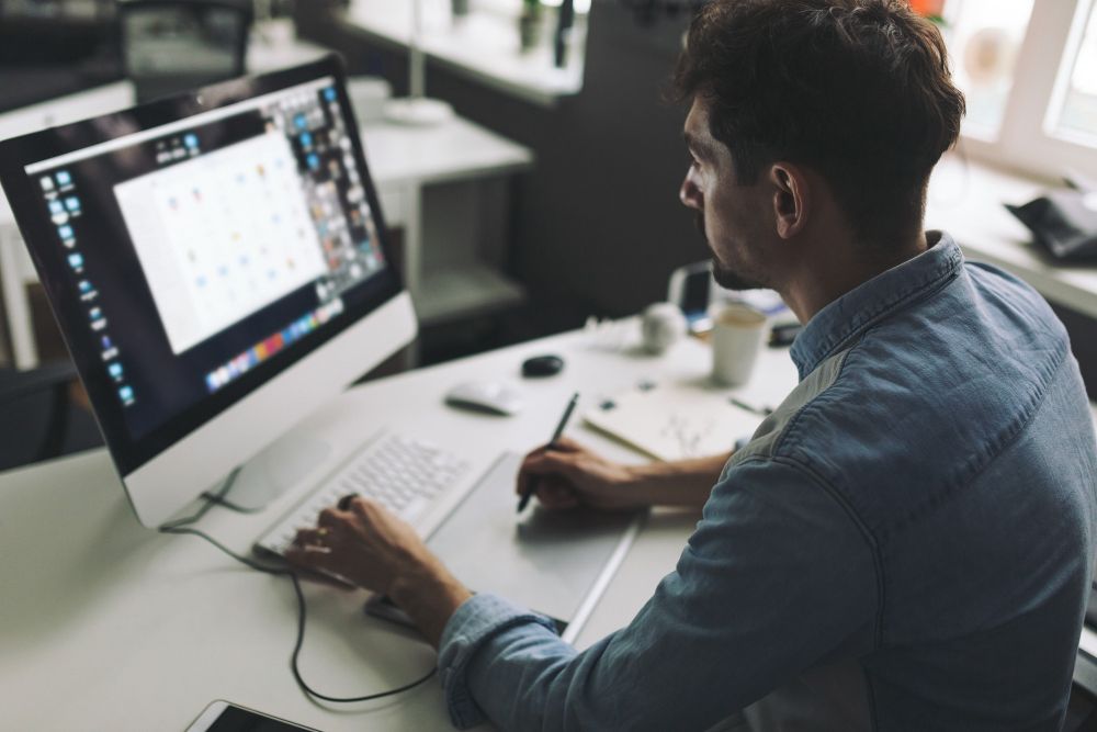 A man is sitting at a desk working on a computer.