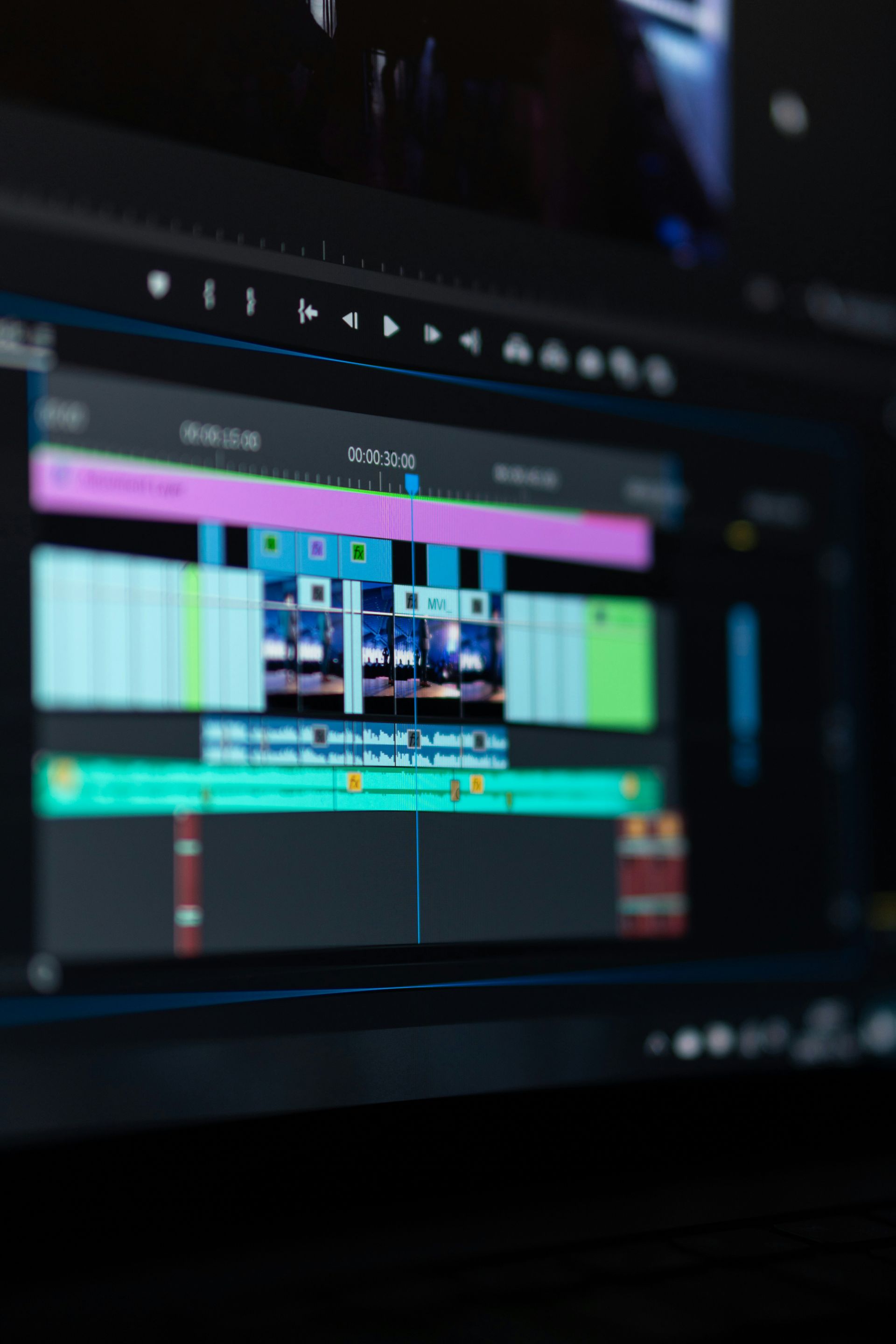 Close-up of a computer screen displaying a video editing software timeline with colorful tracks and video clips.