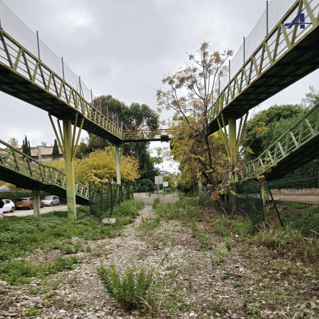 Hay un puente sobre un río en el medio de un campo.