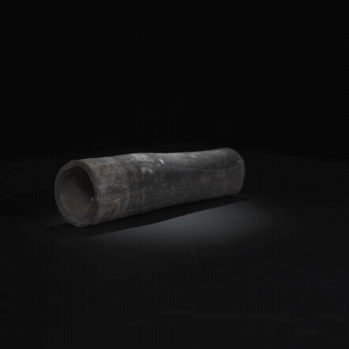 Una tubería negra está asentada sobre una superficie negra en la oscuridad.