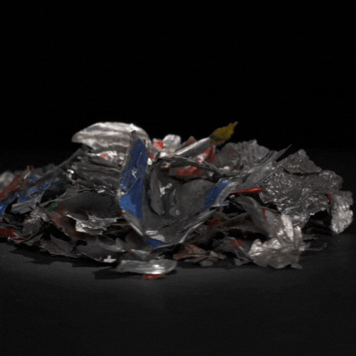 Un montón de latas de aluminio trituradas sobre una superficie negra.