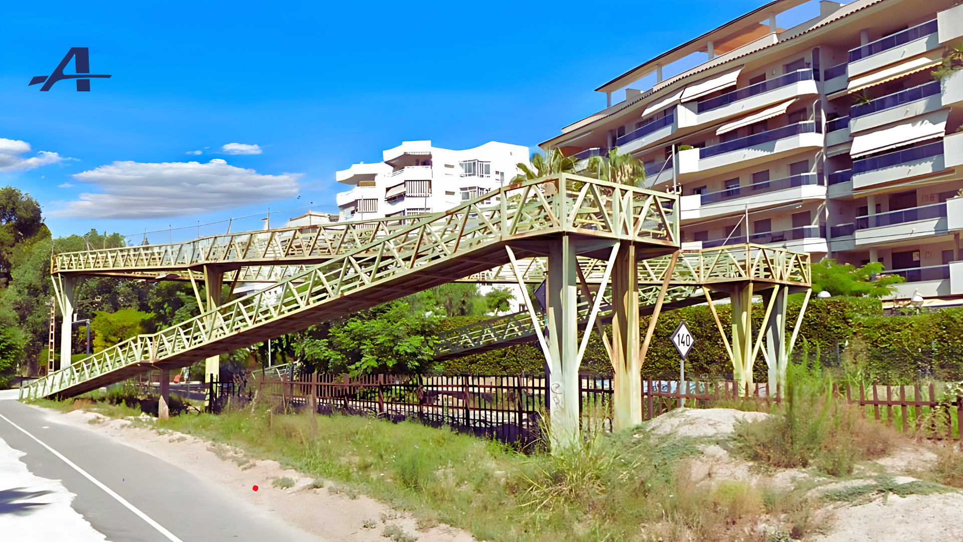 Un puente sobre una carretera con un edificio al fondo.