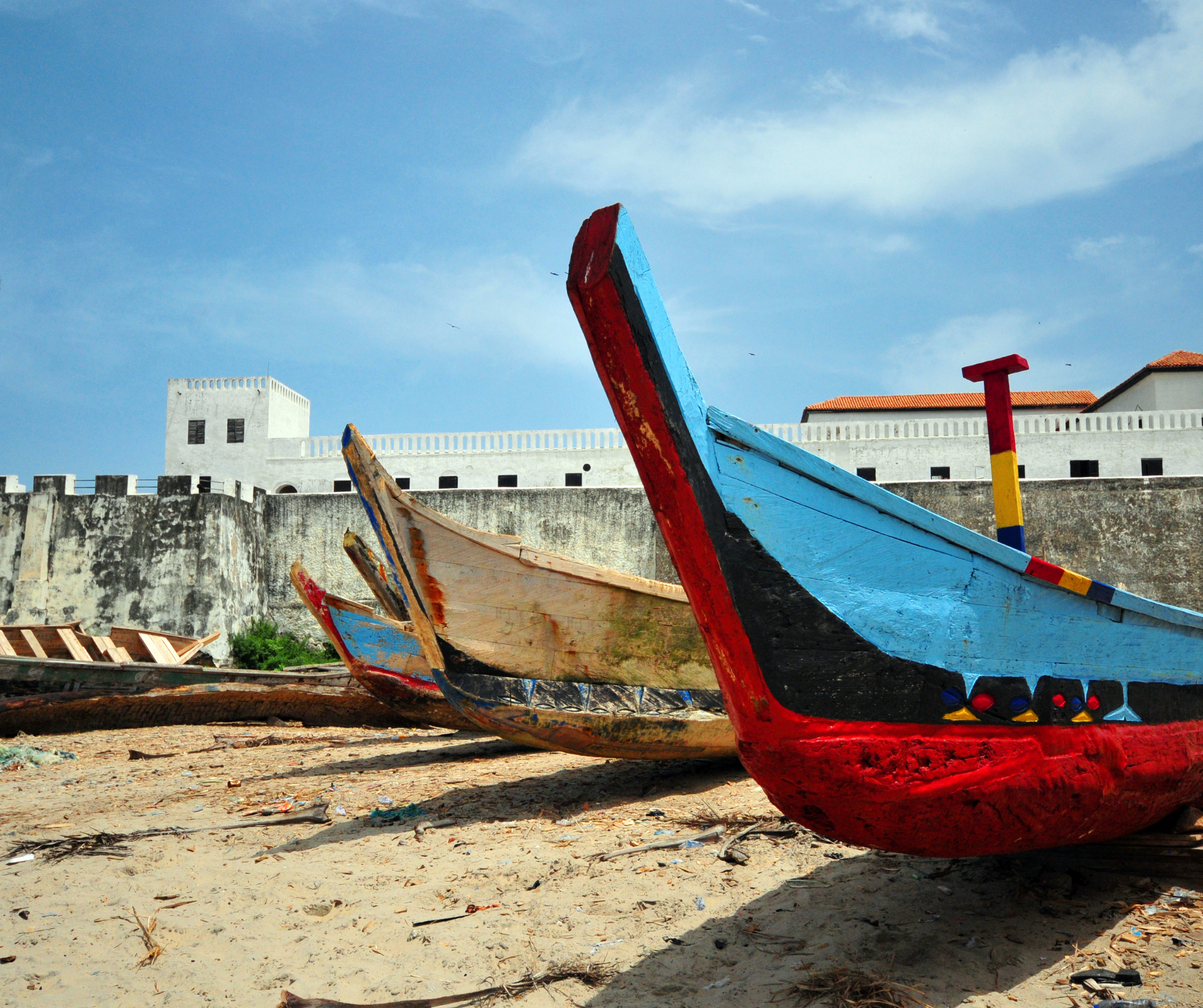 A row of boats are lined up on a sandy beach