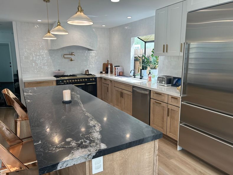 Bright white modern kitchen with island, stainless steel appliances, and black barstools