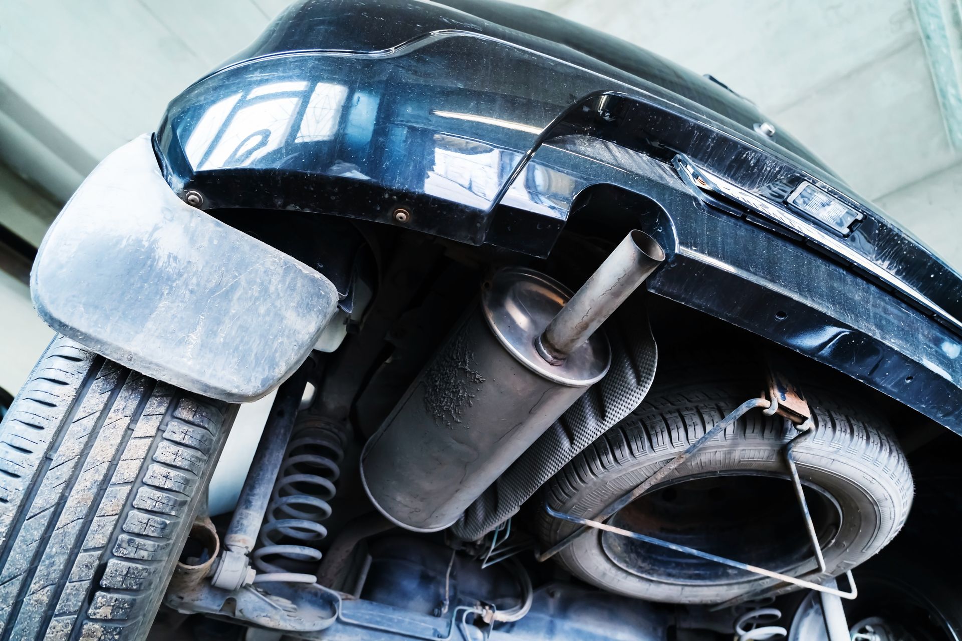 Underbody of a black car showing tire, suspension, and exhaust components