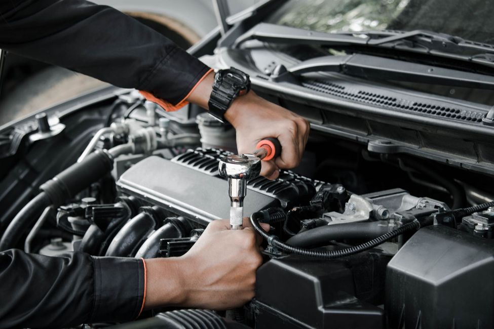 Mechanic using a ratchet wrench to repair a car engine in a garage
