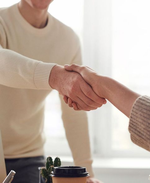 Een man en een vrouw schudden elkaar de hand voor een kopje koffie.