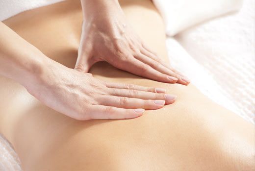 Hands massaging a person's bare back. Close-up on the back, with light skin and the masseuse's hands.