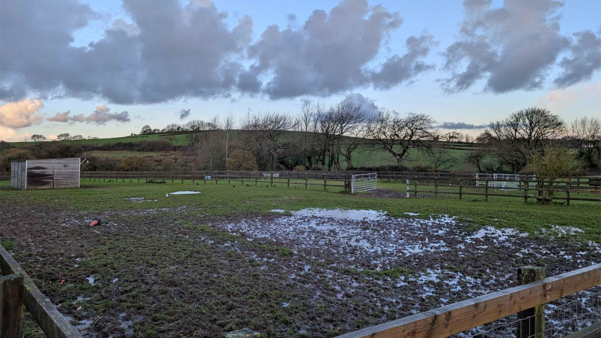 A muddy field with a cloudy sky in the background
